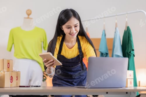Preview: Portrait young attractive Asian female owner startup business working with box at home prepare parce