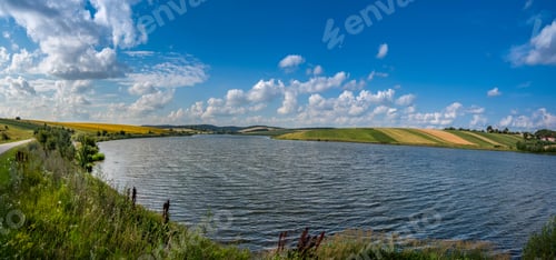 Preview: view across the reservoir to hilly fields with sunflower