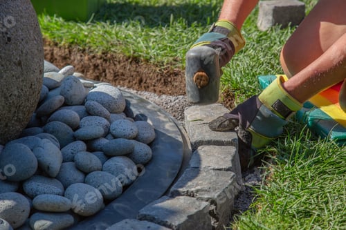 Preview: Closeup shot of a handyman laying cobblestones using a mallet