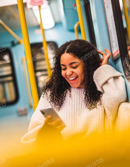Preview: Smiling black woman using smartphone in transport