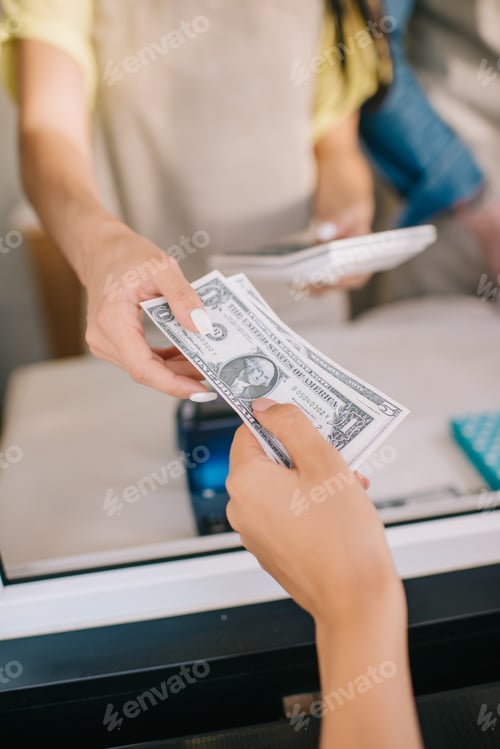 Preview: cropped shot of customer giving dollar banknotes to worker in food truck