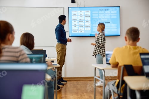 Preview: High school student and her teacher using smartboard during a lecture in the classroom.