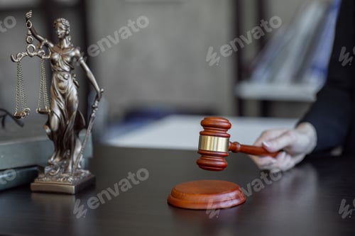 Preview: Statue of Justice and female lawyer in suit at workplace with laptop, gavel and femida in office.