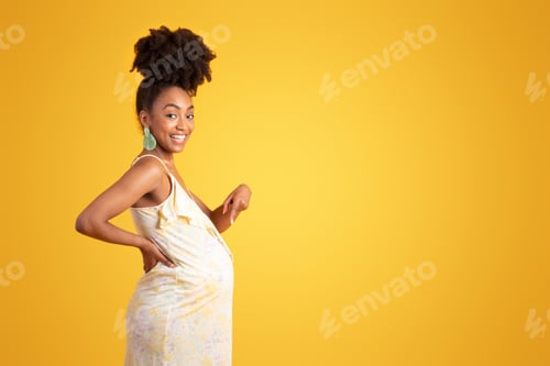 Vista previa: Alegre y orgullosa dama afroamericana milenaria señalando con el dedo una gran barriga