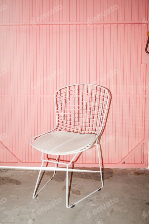 Preview: White Wire Chair in Front of Pink Wall at Indoor Location