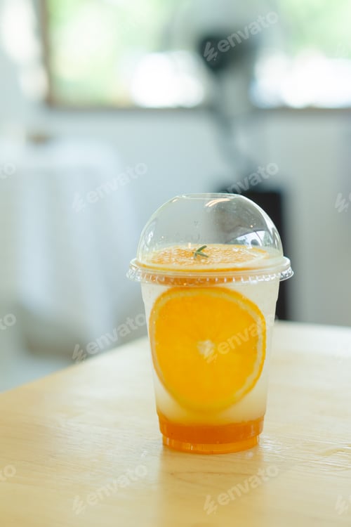 Preview: Glass of ice orange juice with soda on table.