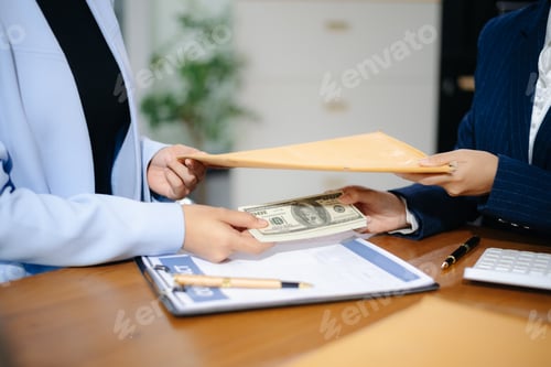 Preview: Two businesswomen in formal suits exchange cash over a contract document in an office. Bribery,