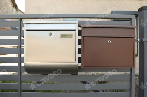 Preview: Different metal letter boxes on fence outdoors