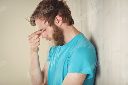 Preview: Troubled hipster leaning against wall in side view