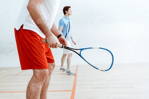 Preview: Partial view of two squash players with rackets in four-walled court