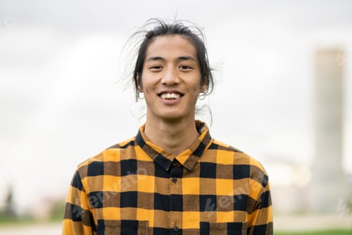 Preview: portrait of a young asian filipino man smiling at camera outdoors