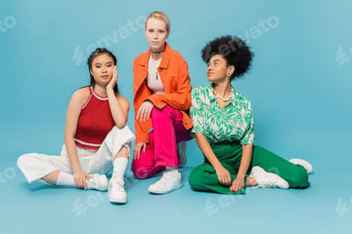 Preview: full length of young blonde woman looking at camera near trendy asian and african american models on