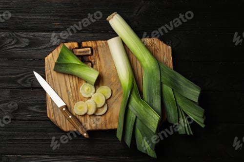 Preview: Fresh raw leeks on black wooden table, flat lay. Ripe onion