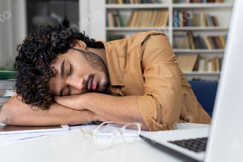 Preview: Tired student sleeping on table inside university academic library, hispanic man among books with