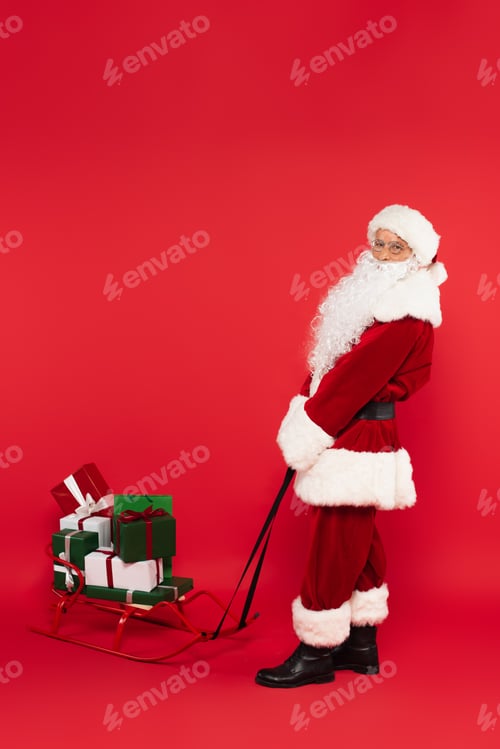 Preview: Santa claus pulling sleigh with presents on red background