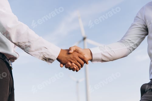 Preview: Engineers shaking hands in front of wind turbines, celebrating sustainable energy