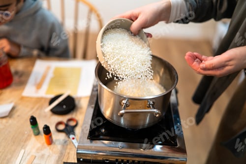 Preview: Hands pouring soy wax pellets for candle making