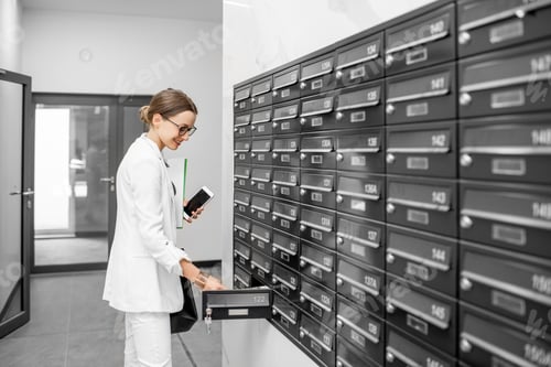 Preview: Woman opening mailbox at the residential building hall
