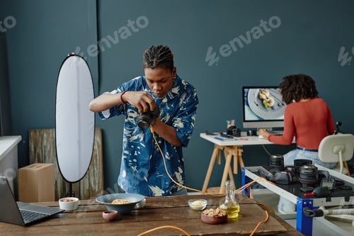 Preview: Young Adult Black Man Photographing Food While Woman Editing Images on Computer