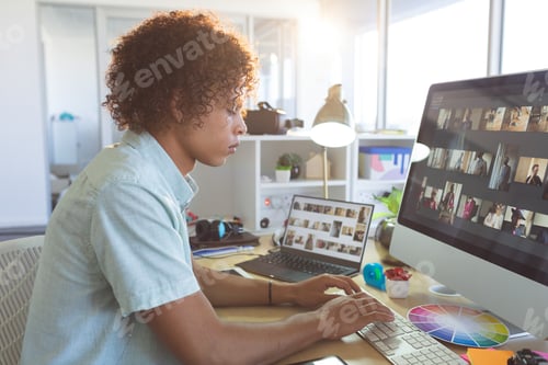 Preview: Male graphic designer typing on computer at desk in modern office