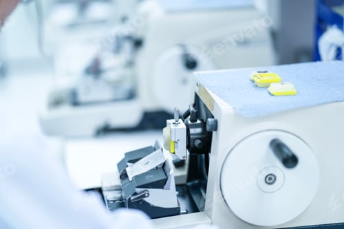 Preview: A female scientist in a lab coat and hair net carefully works with a medical machine
