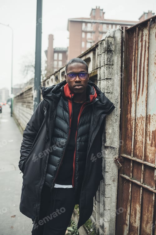 Preview: portrait of young african man standing in the street and looking further