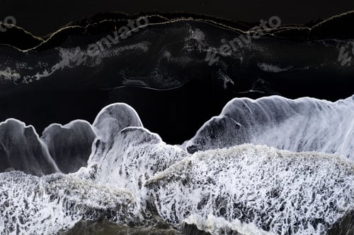 Preview: Aerial view of ocean waves crashing onto a black sand beach, creating a striking contrast