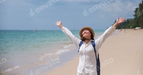 Preview: Portrait of a young woman with hat and backpack open arms by the sea