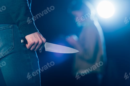 Preview: cropped view of killer holding knife near woman on black