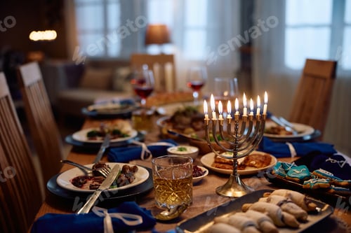Preview: Menorah with lit candles on dining table during Hanukkah celebration.