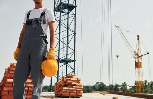 Preview: Close up view. Young construction worker in uniform is busy at the unfinished building