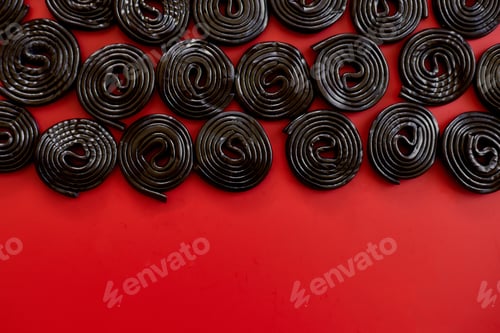 Preview: Flat lay tasty black liquorice candies on red background
