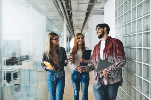 Preview: Cheerful multiethnic colleagues having conversation in office hallway