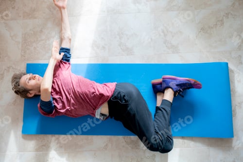 Preview: top overhead view of young man doing stretching at home on the floor