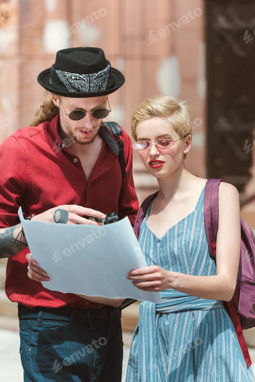 Preview: beautiful couple of tourists looking at map in city