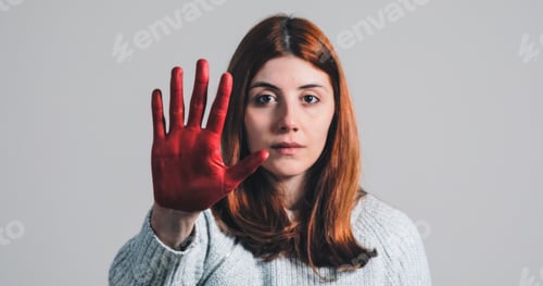 Preview: Sad girl raises her hand painted red to stop and protest against violence