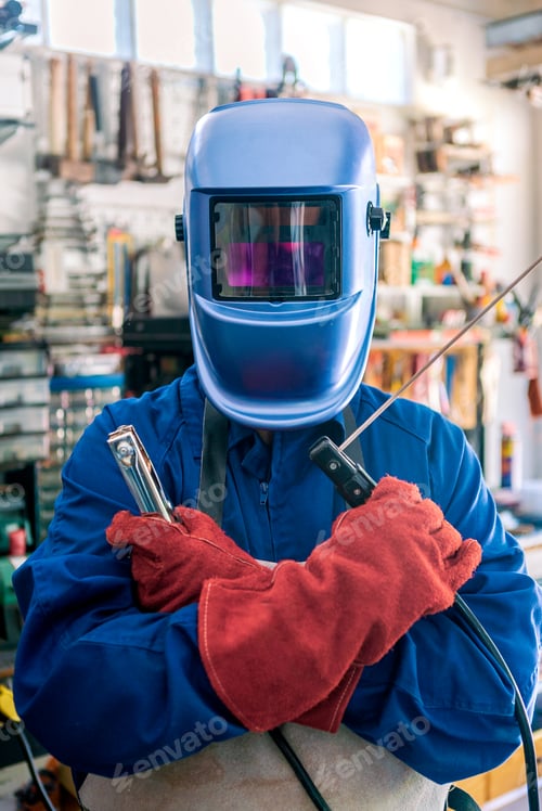 Preview: A man welder with safety helmet working with arc welding machine in the workshop