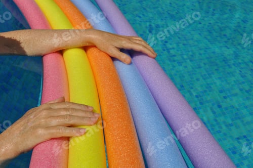 Preview: Hands on rainbow pool noodles in swimming pool