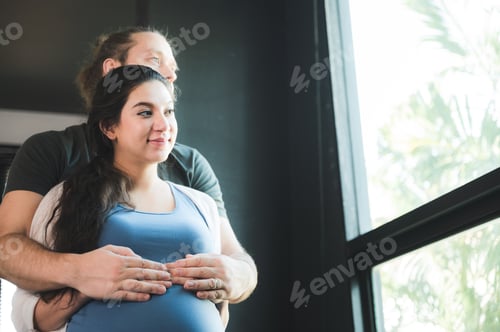 Preview: Happy pregnant couple placing baby shoes on woman big belly and spent time together while resting