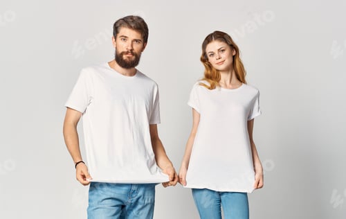 Preview: Portrait of a man and a woman in identical t-shirts teenager jeans light background