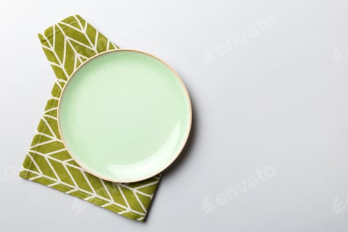 Preview: Top view on colored background empty round green plate on tablecloth for food.