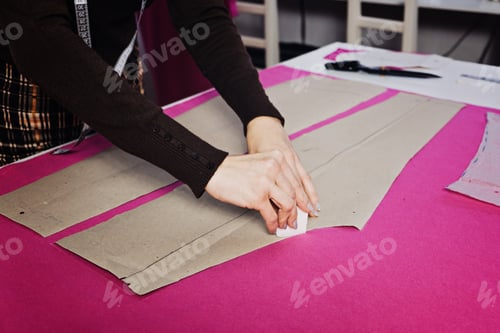 Preview: Female fashion designer tailor making sewing patterns at workplace in sewing studio.