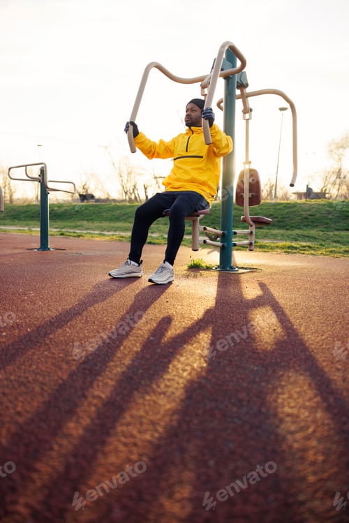 Preview: Man exercising on pec machine while working out in an outdoor gym