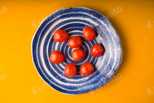 Preview: Cherry tomatoes plate on yellow wooden table. Top view