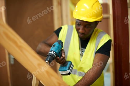 Preview: Male higher education student drilling wooden framework in college workshop