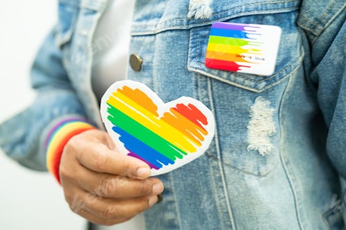 Preview: Asian lady wearing rainbow flag wristbands and hold red heart, symbol of LGBT pride month celebrate