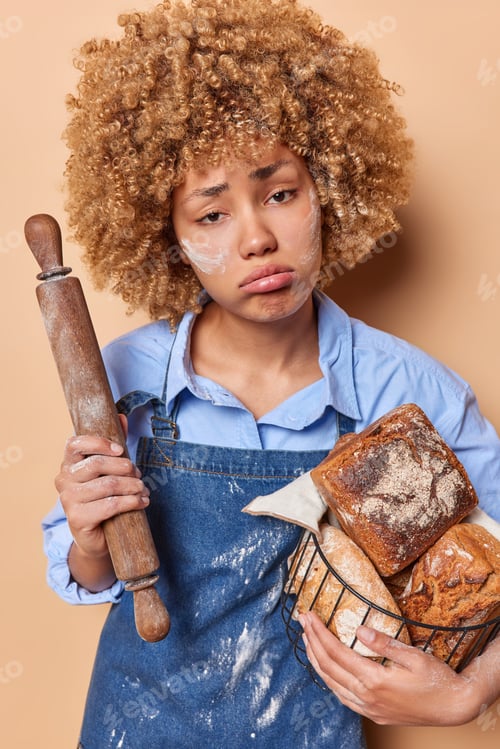 Preview: Unhappy tired woman poses with baked delicious yeast free bread feels exhausted after long process