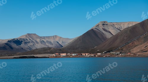 Preview: Serene view of Pyramiden settlement reflecting on water in Svalbard under clear blue skies