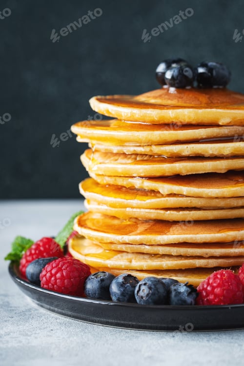 Preview: Delicious pancakes, with fresh blueberries, raspberry and maple syrup or honey on a dark background