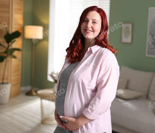 Preview: Beautiful pregnant woman touching her belly at home